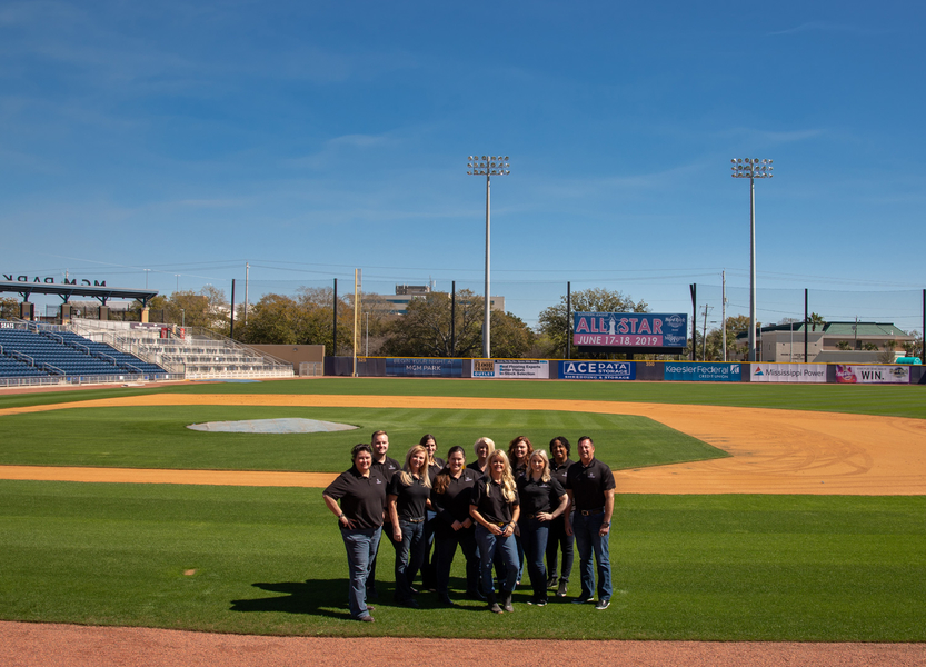 HL Raymond Properties real estate experts standing on a baseball field during their giving back project